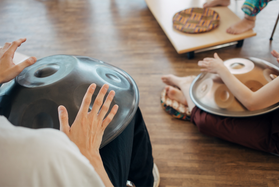 Zwei junge Menschen spielen Handpan. Nur die Instrumente und ihre Hände sind zu sehen.